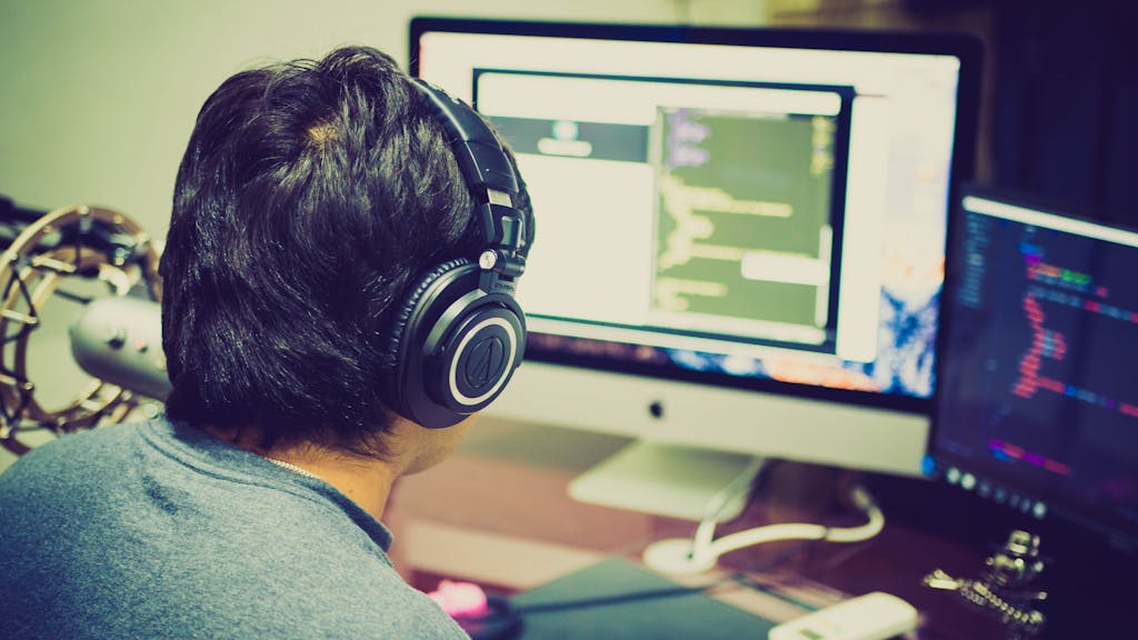 An oddsmaker and data analyst working on sports betting projections using dual monitors and machine learning code.