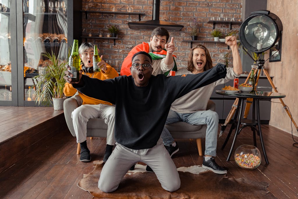 Group of diverse friends celebrating a sports event indoors with drinks and snacks.