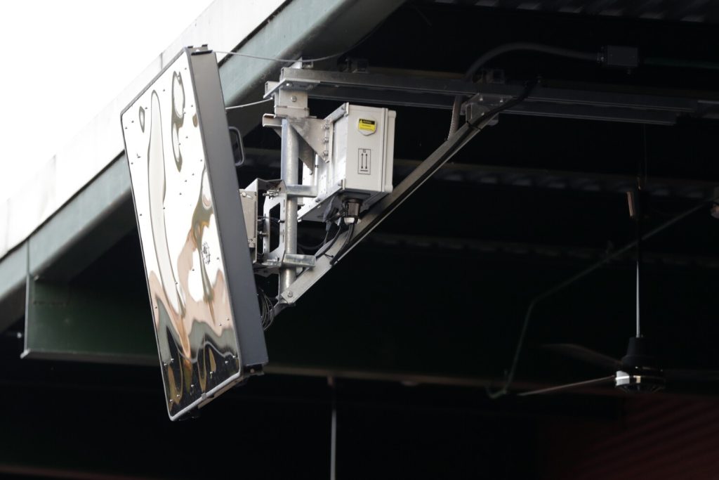 FILE -A radar device is seen on the roof behind home plate at PeoplesBank Park during the third inning of the Atlantic League All-Star minor league baseball game, Wednesday, July 10, 2019, in York, Pa. Major League Baseball will test robot umpires as part of a challenge system during spring training at 13  ballparks hosting 19 teams, which could lead to regular-season use in 2026. (AP Photo/Julio Cortez, File)